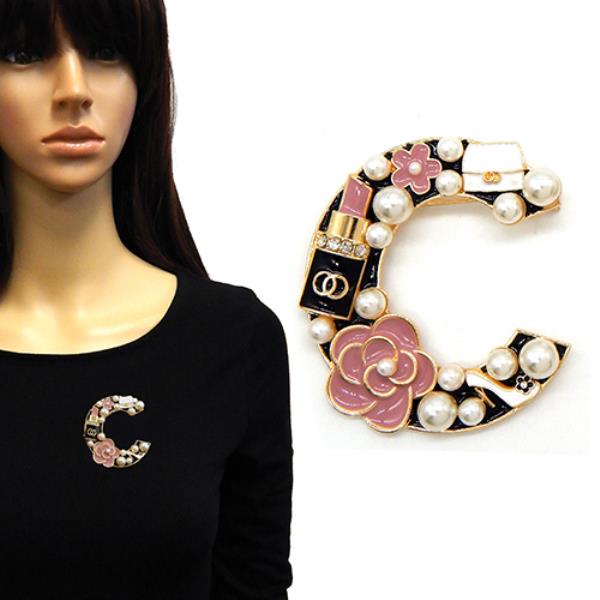 C-SHAPED BROOCH FEATURING FLOWERS, WHITE PEARLS, A LIPSTICK CHARM, AND A PURSE